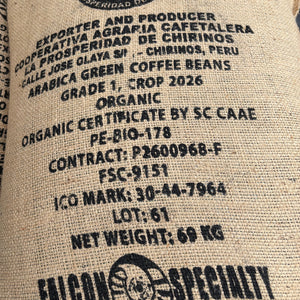 Close-up of a large beige burlap coffee bag printed with black text and logos. Visible text includes 'Falcon Specialty', 'Cooperativa Agraria Cafetalera La Prosperidad De Chirinos', 'Arabica Green Coffee Beans', 'Grade 1, Crop 2026', 'Organic'