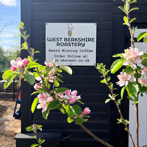 West Berkshire Roastery sign on a building with flowering branches in the foreground