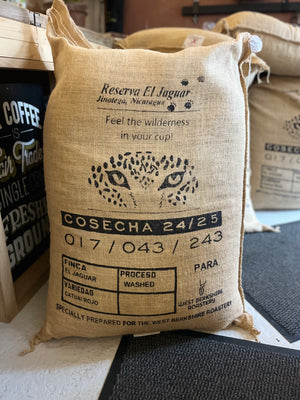 Burlap coffee bag with branding and text on a wooden surface