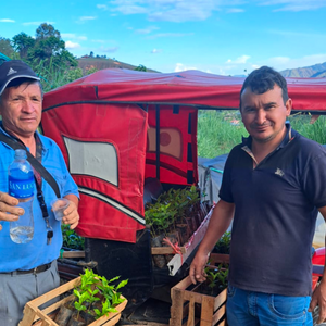 Two men standing outdoors with a red truck in the background